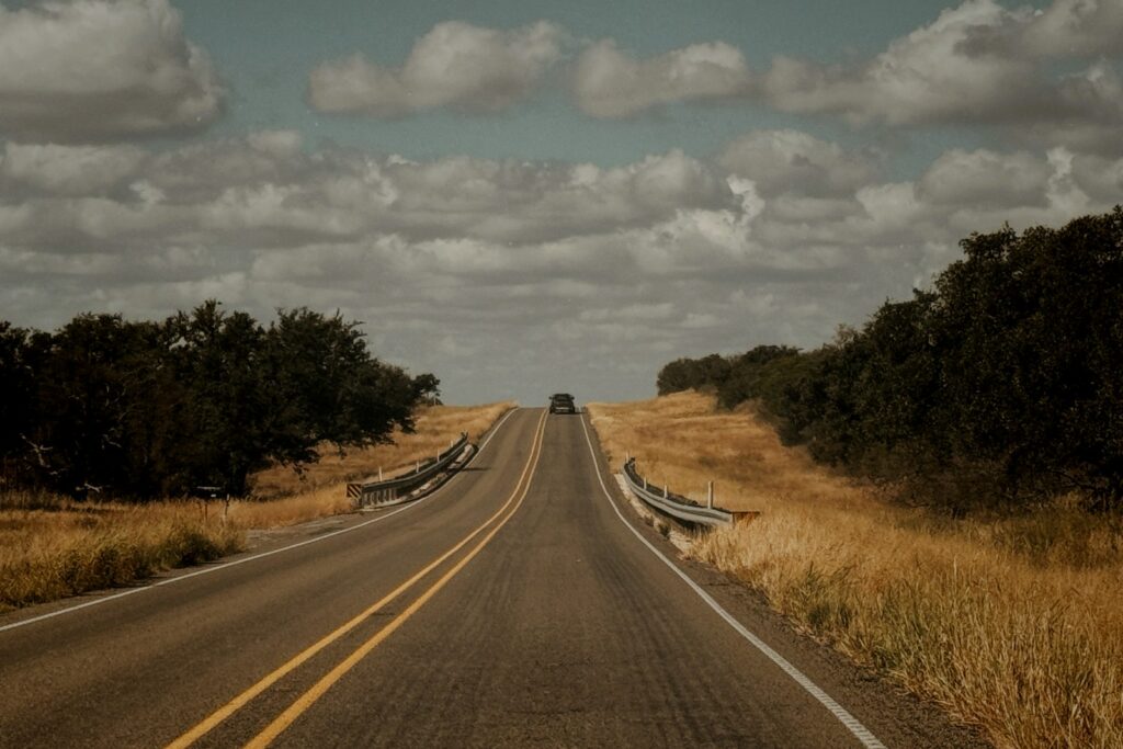 An empty stretch of Texas highway bordered by a roadside fence