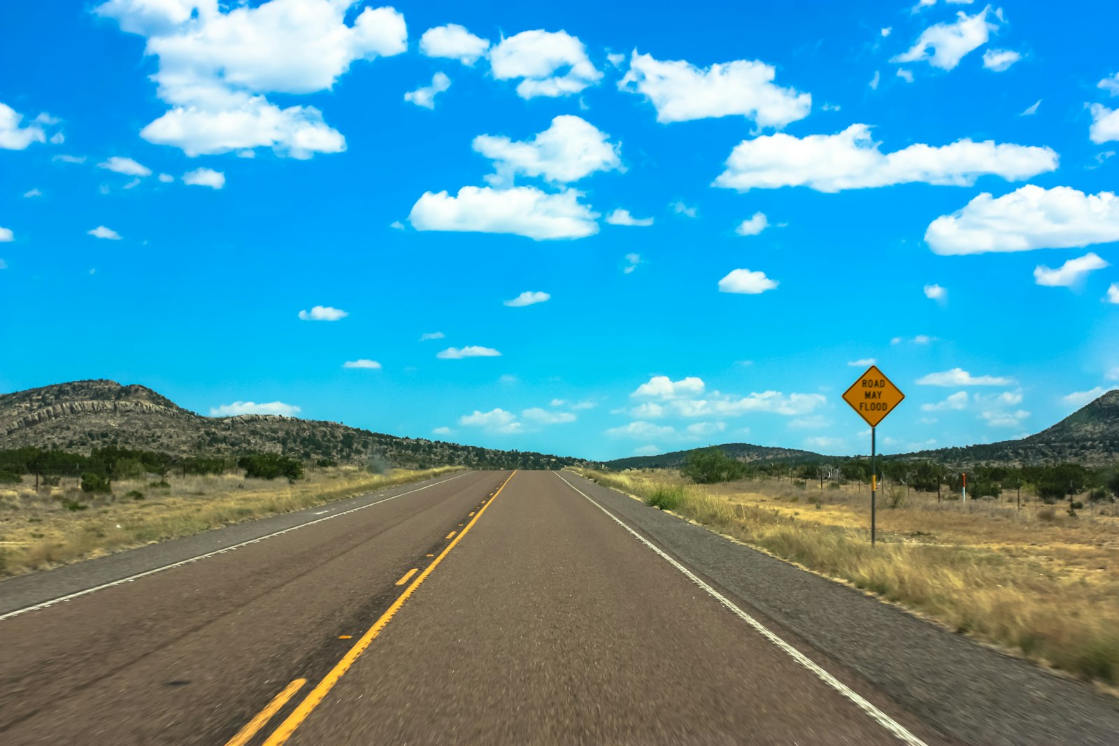 A yellow warning sign posted on the side of a Texas road